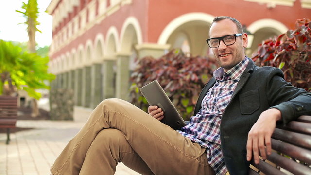 Young man in tourist resort with tablet computer smiling to the 