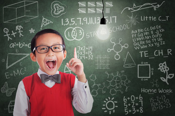 Asian boy has idea under lit bulb in classroom
