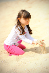 Fototapeta na wymiar Adorable toddler girl playing on white sand beach.
