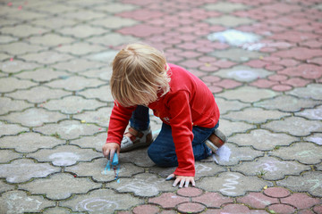 Preschooler child drawing with chalk on sidewalk