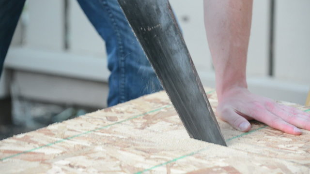 Angled view of man sawing wood plank