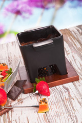 Chocolate fondue with fresh fruits on wood
