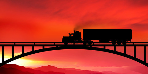 Silhouette of a truck on a bridge at sunset