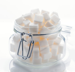 glass jar full of white sugar cubes on white base