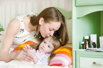 mother kisses the sick child