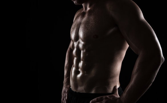 Close up of perfect male body isolated on black background