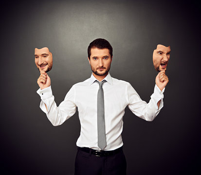 man holding two masks with different mood