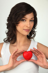 Young brown-haired woman with red heart in hands