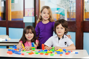 Fototapeta premium Cute Friends With Blocks On Desk In Classroom