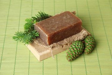 Hand-made soap and green pine cones on bamboo mat