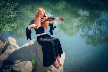 portrait of the rural red-haired girl with a violin