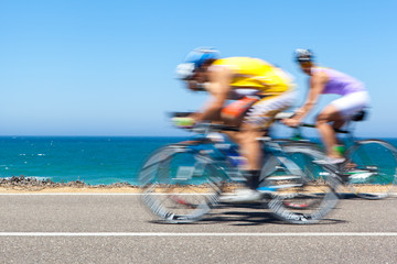 Radfahrer, die entlang einer Küstenstraße konkurrieren