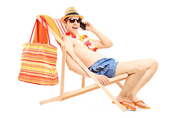 Man enjoying on a sun lounger while talking on a mobile phone