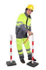 Construction worker putting up a barrier