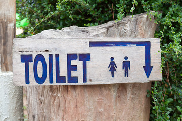 Fototapeta premium A wooden sign hung over the entrance to a toilet