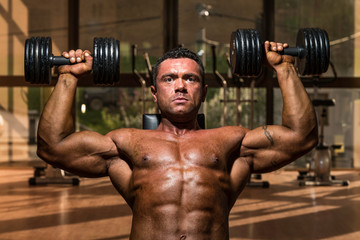 Fototapeta na wymiar male bodybuilder doing shoulder press whit dumbbell