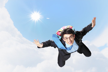 Young businessman flying with parachute on back