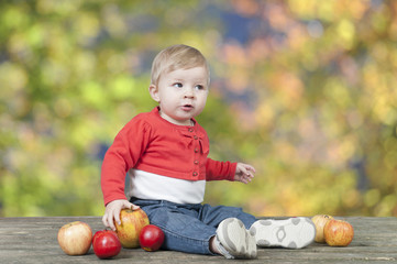 Fototapeta premium baby with apples, seated on a old wooden table