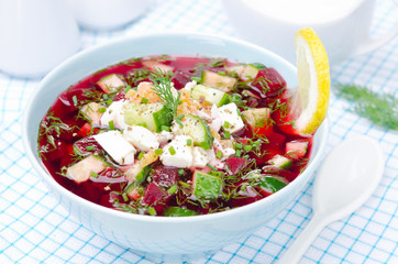 cold beetroot soup with cucumbers, eggs and herbs in a blue bowl