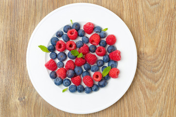 Fresh raspberries and blueberries on a plate top view