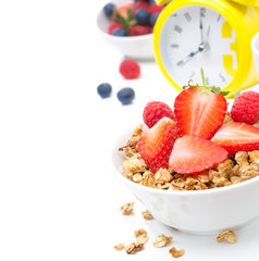 Granola with fresh berries for breakfast and yellow alarm clock