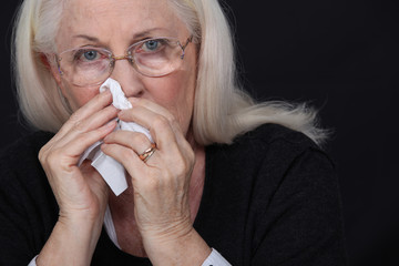 Elderly woman blowing her nose