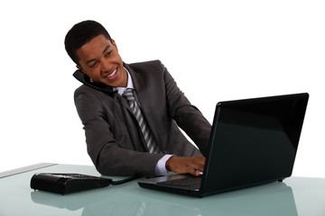 Businessman typing whilst on telephone call