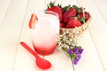Delicious strawberry yogurt in glass on wooden table close-up