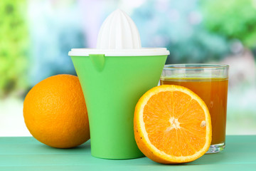 Citrus press, glass of juice and ripe orange