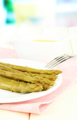 Asparagus on plate, on wooden table on bright background