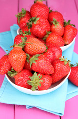 Fresh strawberry in bowl on pink wooden background