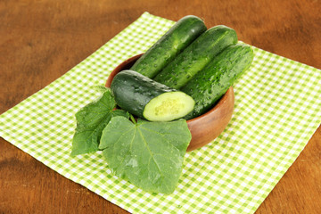 Tasty green cucumbers on color napkin, on wooden background