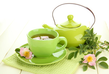 Cup and teapot of herbal tea with hip rose flowers