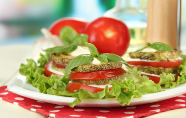 Tasty roasted marrow and tomato slices with salad leaves,