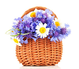 Beautiful bouquet of cornflowers and chamomiles in basket,