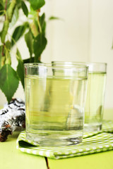 Glasses of birch sap on green wooden table