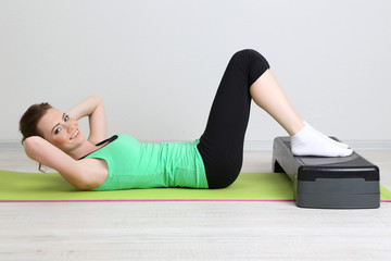 Fototapeta premium Beautiful young woman exercises on stepper