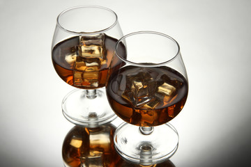 Brandy glasses with ice on grey background