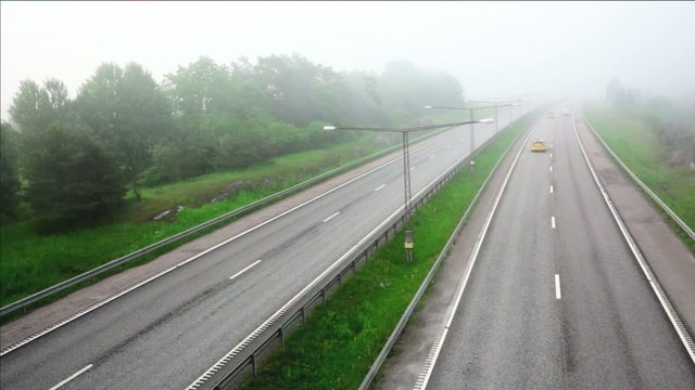 motorway with fast traffic on foggy morning