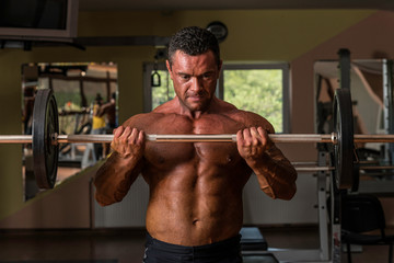 bodybuilder doing heavy weight exercise for biceps with barbell