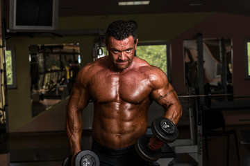 Fototapeta na wymiar bodybuilder doing heavy weight exercise for biceps with dumbbell