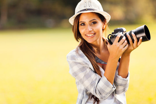 attractive young woman holding camera outdoors