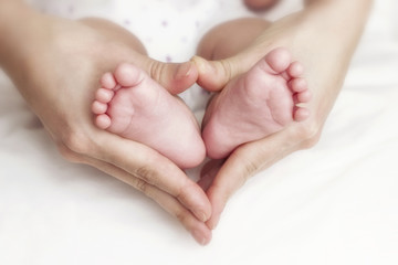 Obraz na płótnie Canvas Noworodki stopy dziecka w rękach matki
