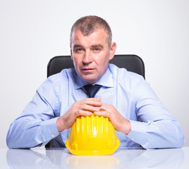 old business man sits with hands on helmet
