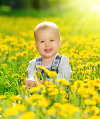 happy baby girl on  meadow with yellow flowers  on the nature
