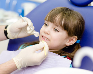 dental examining being given to little girl by dentist