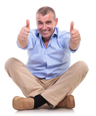 casual middle aged man sits and shows thumbs up