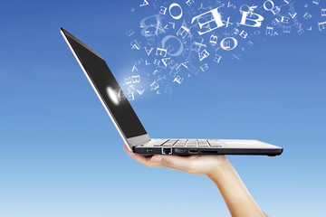 Alphabet letters flying from laptop screen outdoor