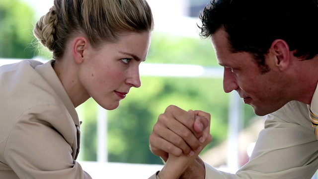 Businesswoman and businessman arm wrestling
