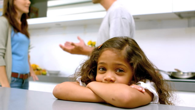 Sad girl with arms folded while parents quarreling